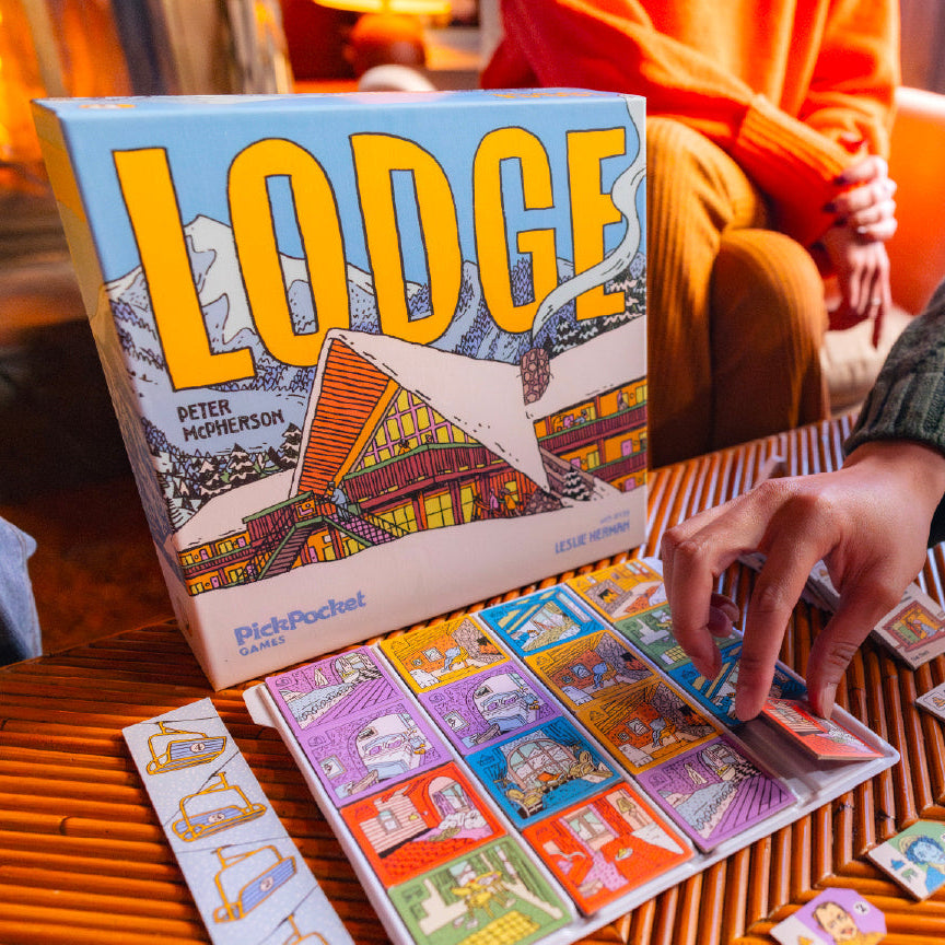 Person playing a board game titled 'Lodge' with colorful game pieces on a wooden table.